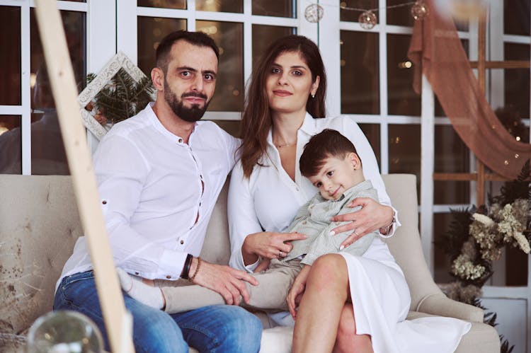 Couple Sitting On Couch On Porch Holding Their Son