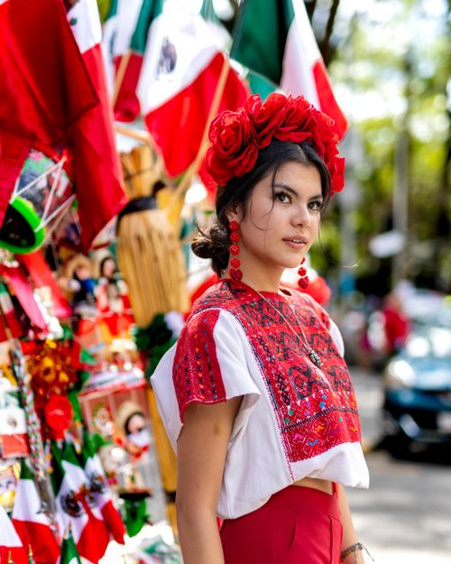 Free A woman wearing traditional Mexican clothing amidst vibrant flags and decor. Stock Photo