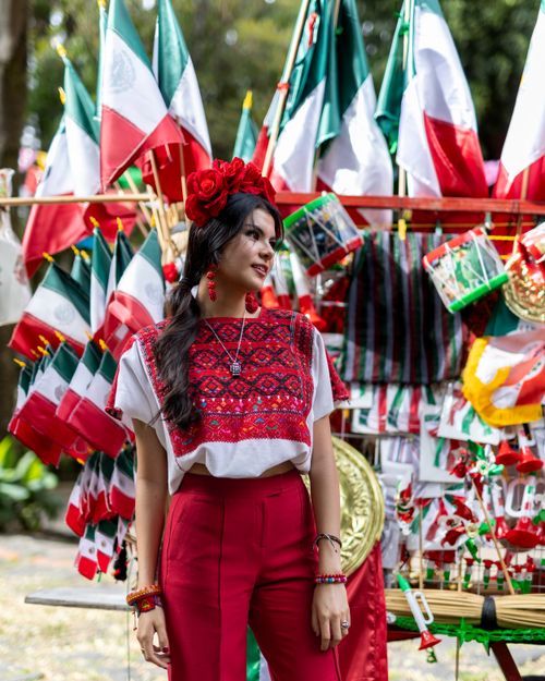 Free Woman in traditional attire amid Mexican flags during a festive outdoor celebration. Stock Photo