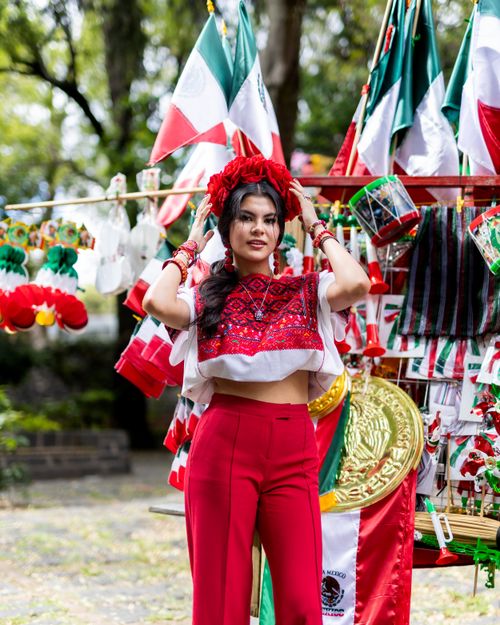 Free A woman in traditional Mexican attire with flags, celebrating outdoors. Stock Photo