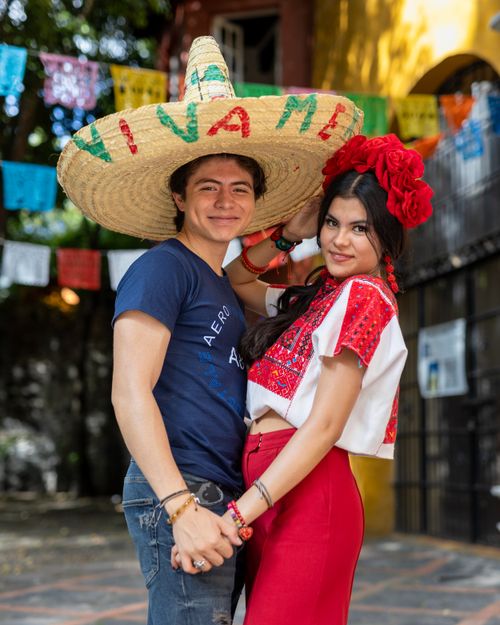 Free A young couple in traditional Mexican attire celebrating outdoors with festive decorations. Stock Photo