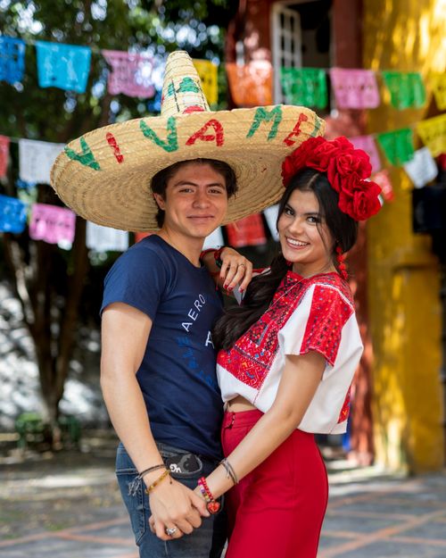 Free Joyful couple in traditional Mexican attire embracing celebration spirit outdoors. Stock Photo