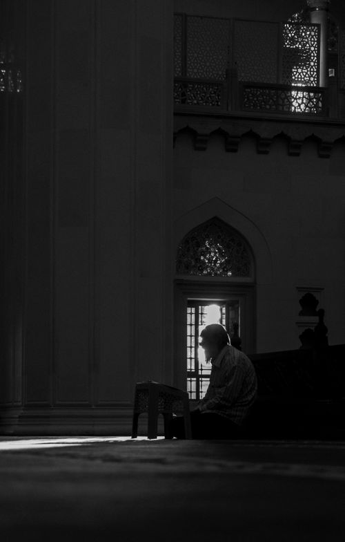 Free A man praying inside a mosque captured in dramatic black and white. Stock Photo