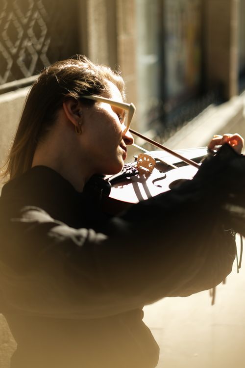 Free Young woman plays violin on a sunlit street in Ankara, capturing a serene musical moment. Stock Photo