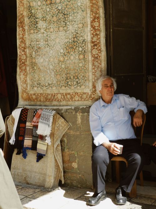 Free Elderly man sitting outside a shop with a drink, enjoying the sunlight. Stock Photo
