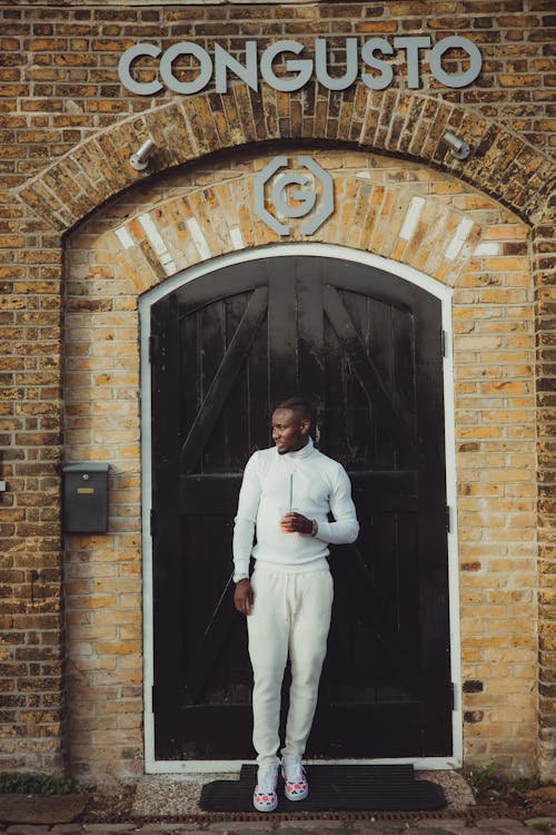 Man in a White Outfit Standing in front of the Door