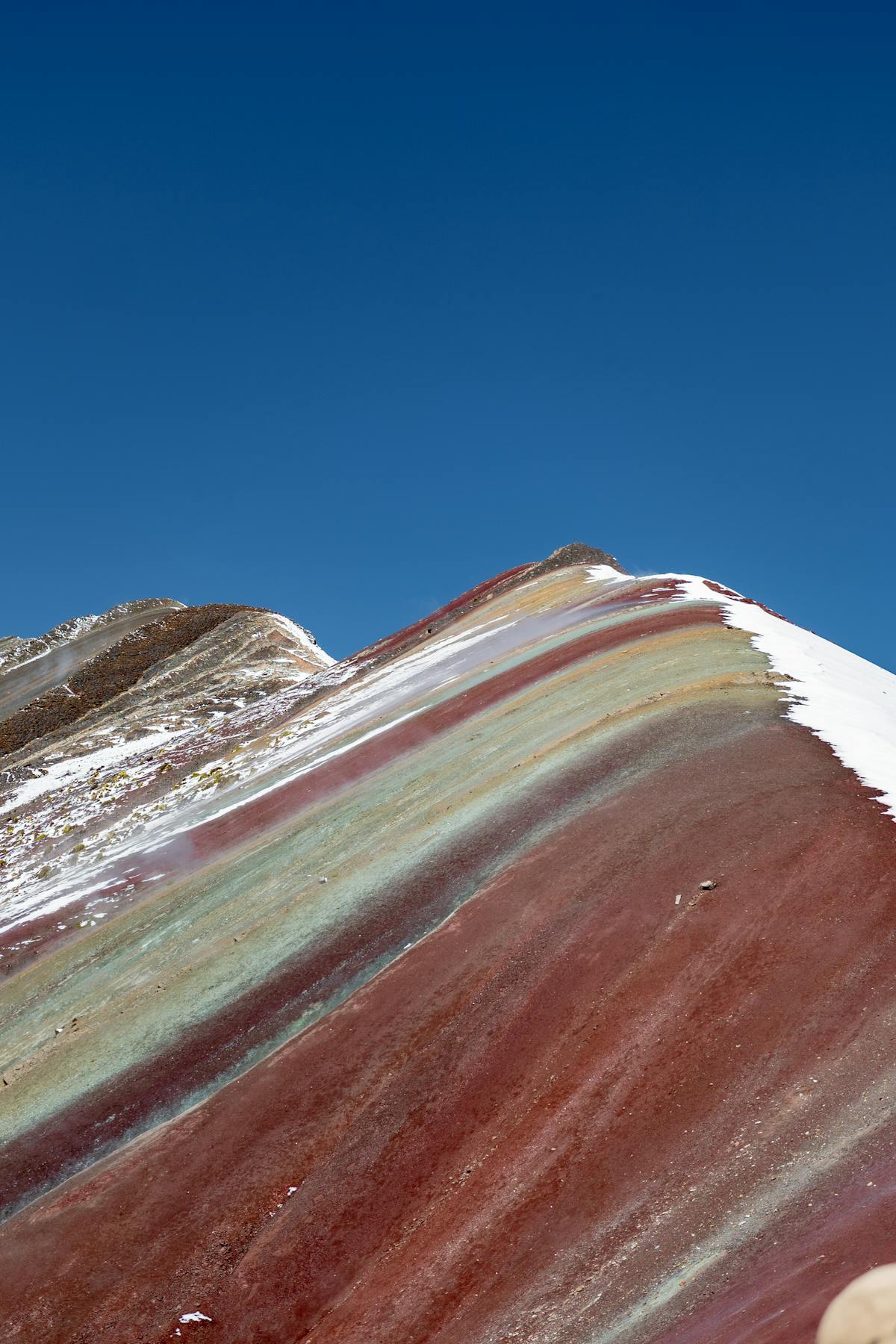 Colourful striped slopes of Vinicunca Rainbow Mountain with hikers on the trail in Peru