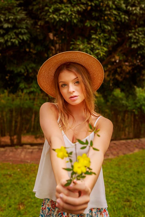 Woman in Spaghetti Strapped Shirt Holding Yellow Flowers