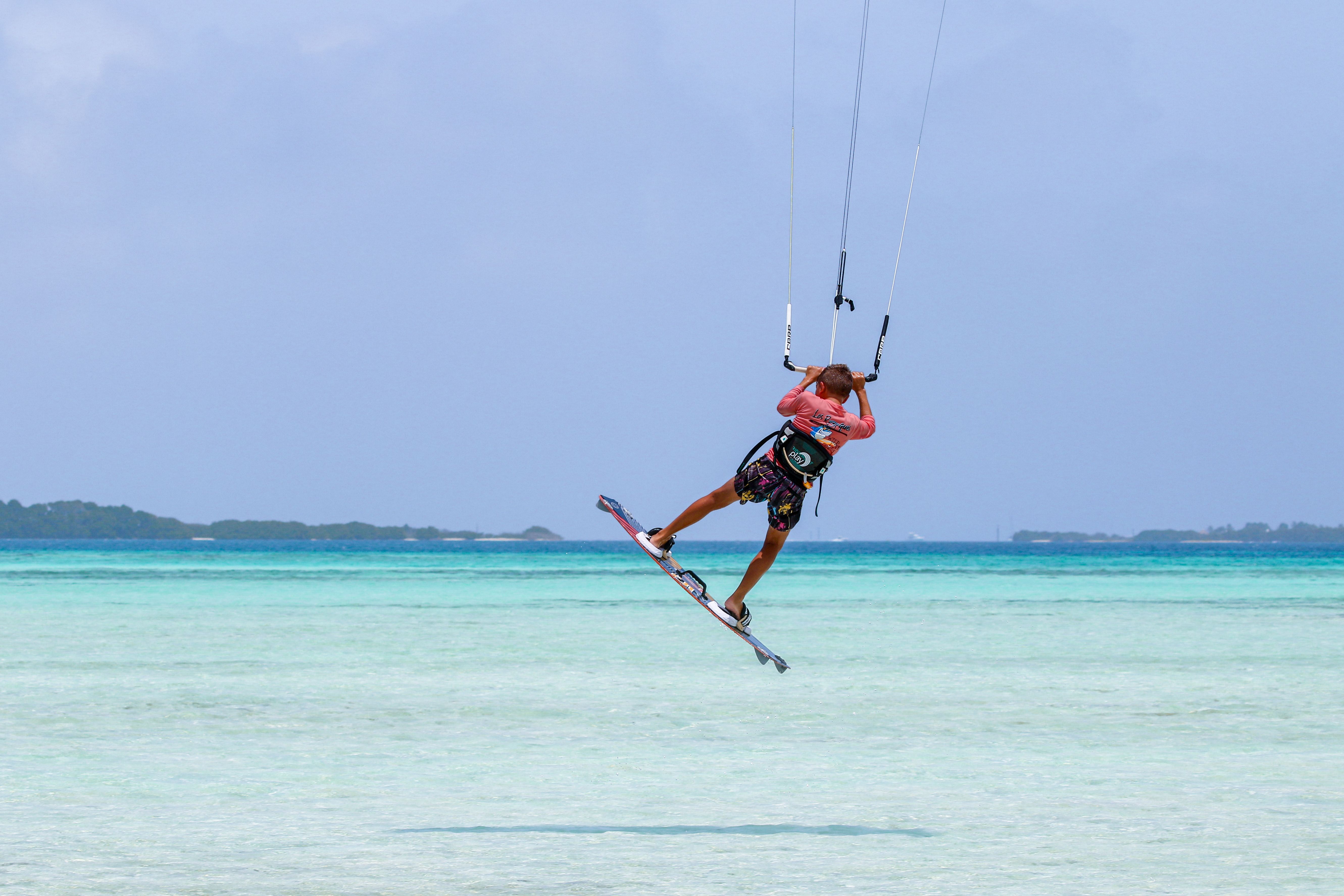 Kitesurfer performing a thrilling maneuver over crystal-clear turquoise waters. - Silver Sands Beach: The Ultimate Guide for Kite Surfing