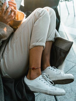 Close-up of a person sitting comfortably with white sneakers and a colorful anklet