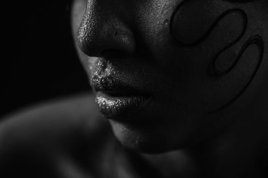 Black and white close-up of a woman's face with artistic lighting and textured details.