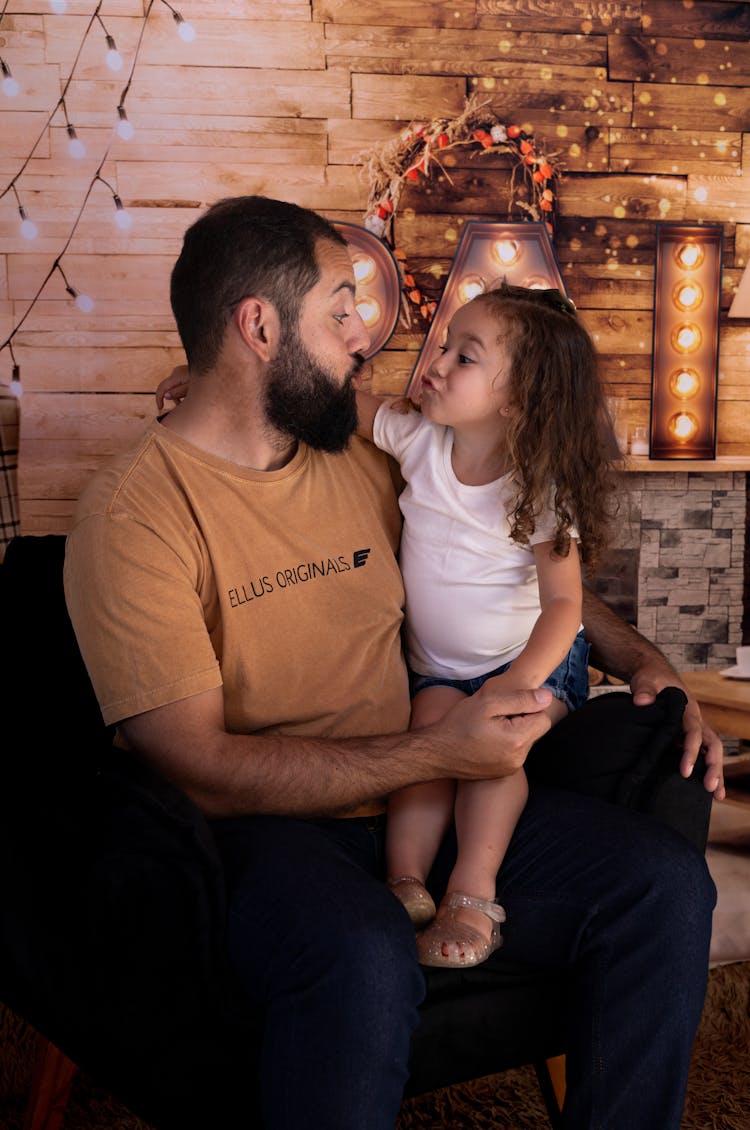 Little Girl Sitting On Father Lap Making A Face