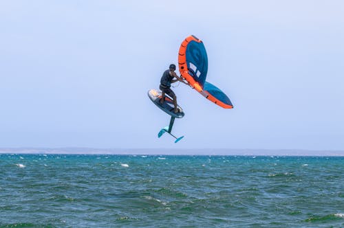 Man Windsurfing and Jumping over Sea Shore