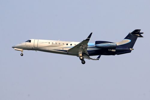 Free Embraer Legacy 600 private jet flying in clear blue sky, showcasing sleek design and elegance. Stock Photo