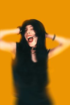 A woman with black hair appears shouting, hands on her head, against a dynamic yellow background.