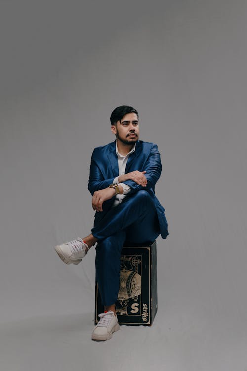 Man in Blue Suit Sitting and Posing on Box