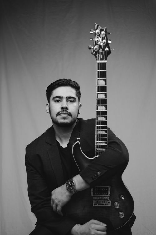 Free Black and white portrait of a man in a suit holding a guitar, exuding elegance. Stock Photo