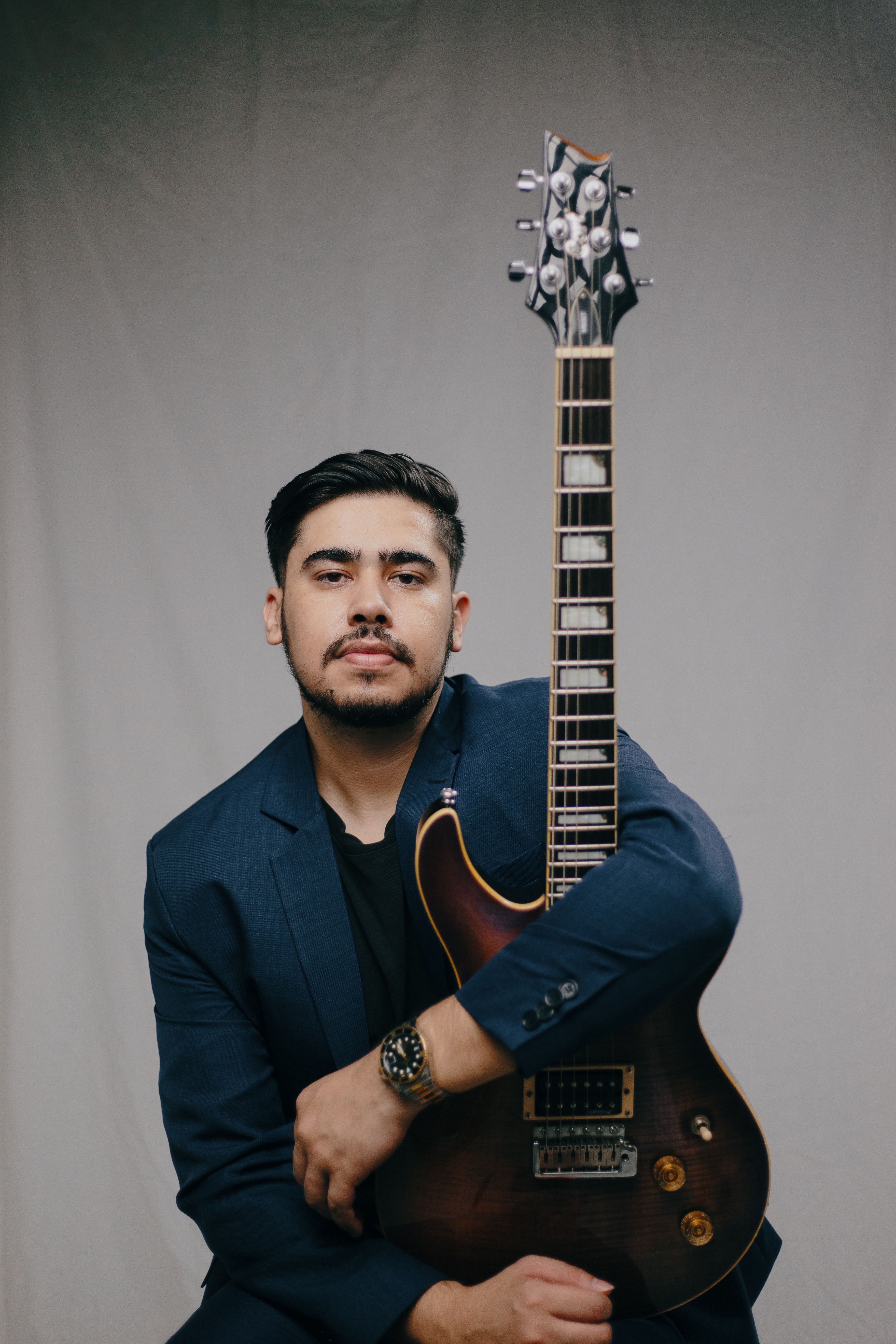 A stylish man poses with an electric guitar in a studio setting. Perfect for music and fashion themes.