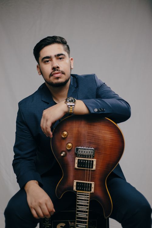Free Stylish man holding an electric guitar, posing for a portrait on a gray background. Stock Photo
