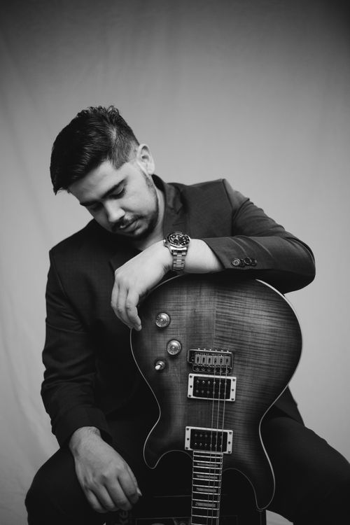 Free Black and white portrait of a man holding a guitar, sitting and looking down. Stock Photo