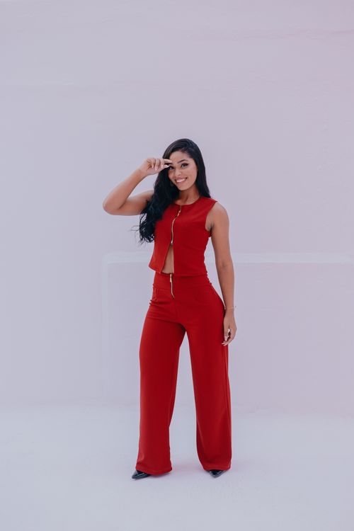 Free Stylish woman in a red suit poses in a studio with a minimalist background. Stock Photo