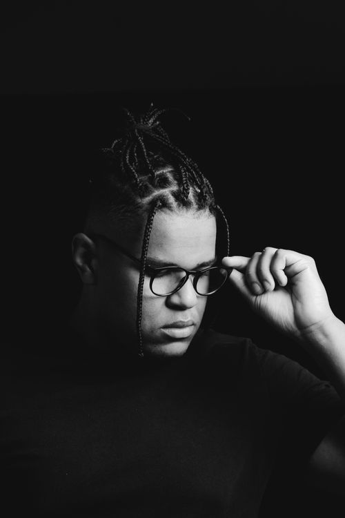 Free Monochrome portrait of a man adjusting his eyeglasses while looking down thoughtfully. Stock Photo