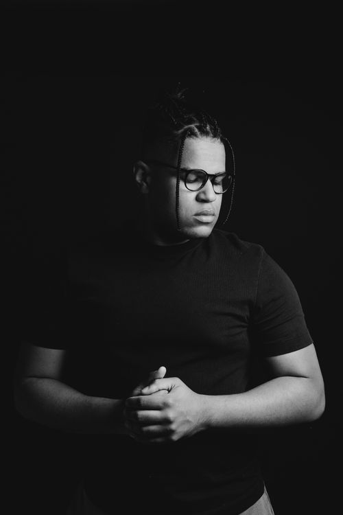 Free Moody black and white portrait of a man with glasses and dreadlocks in a thoughtful pose. Stock Photo