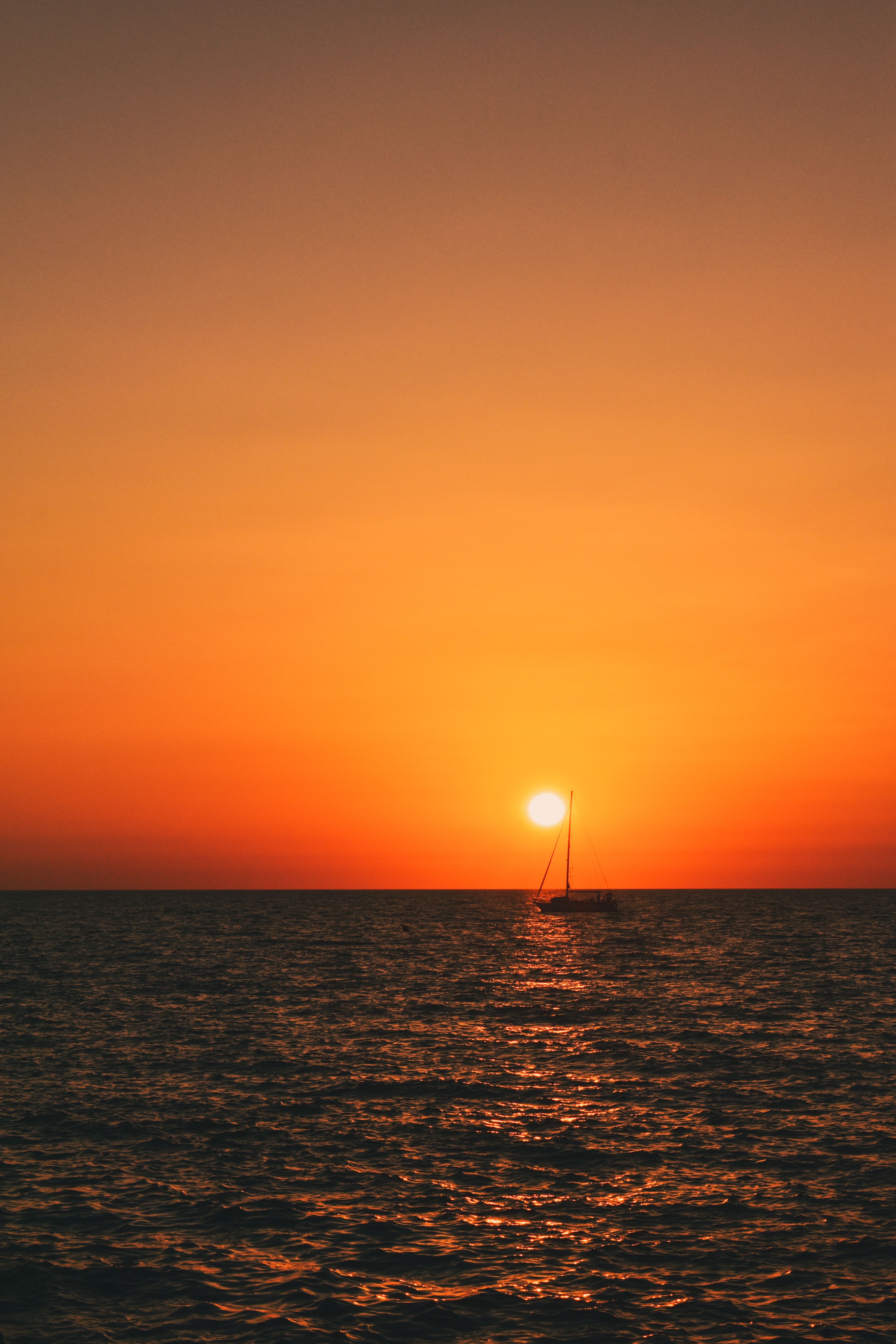 Yellow, Sunset Sky over Sea Coast with Sailboat behind · Free Stock Photo