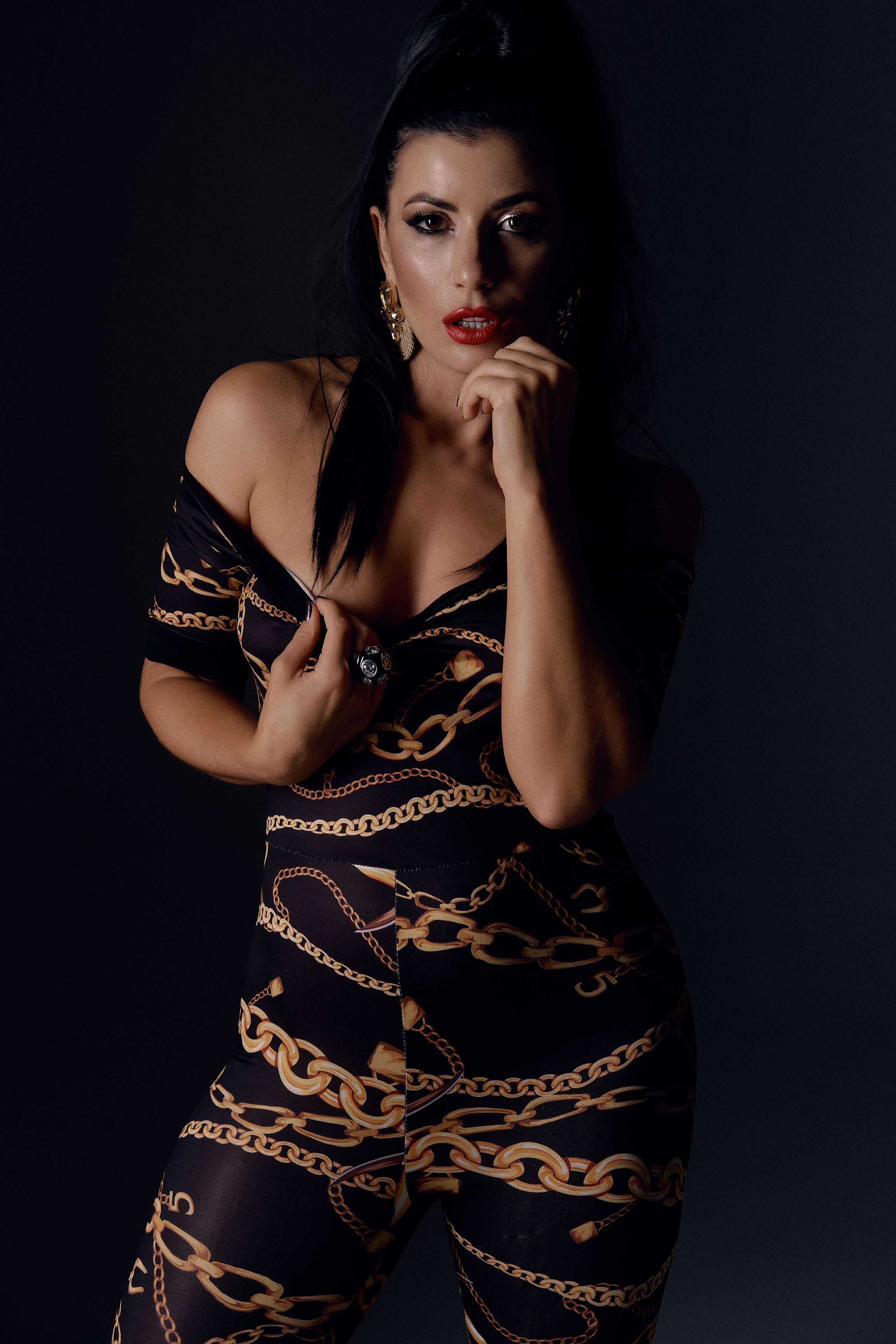 Stylish portrait of a woman in a chain pattern outfit on a dark background.