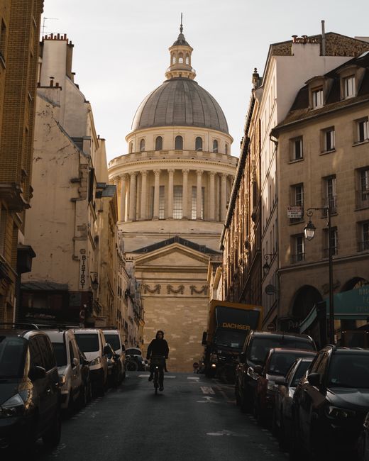 A breathtaking view of the Panthéon in Paris framed by historic buildings under a dramatic sky.