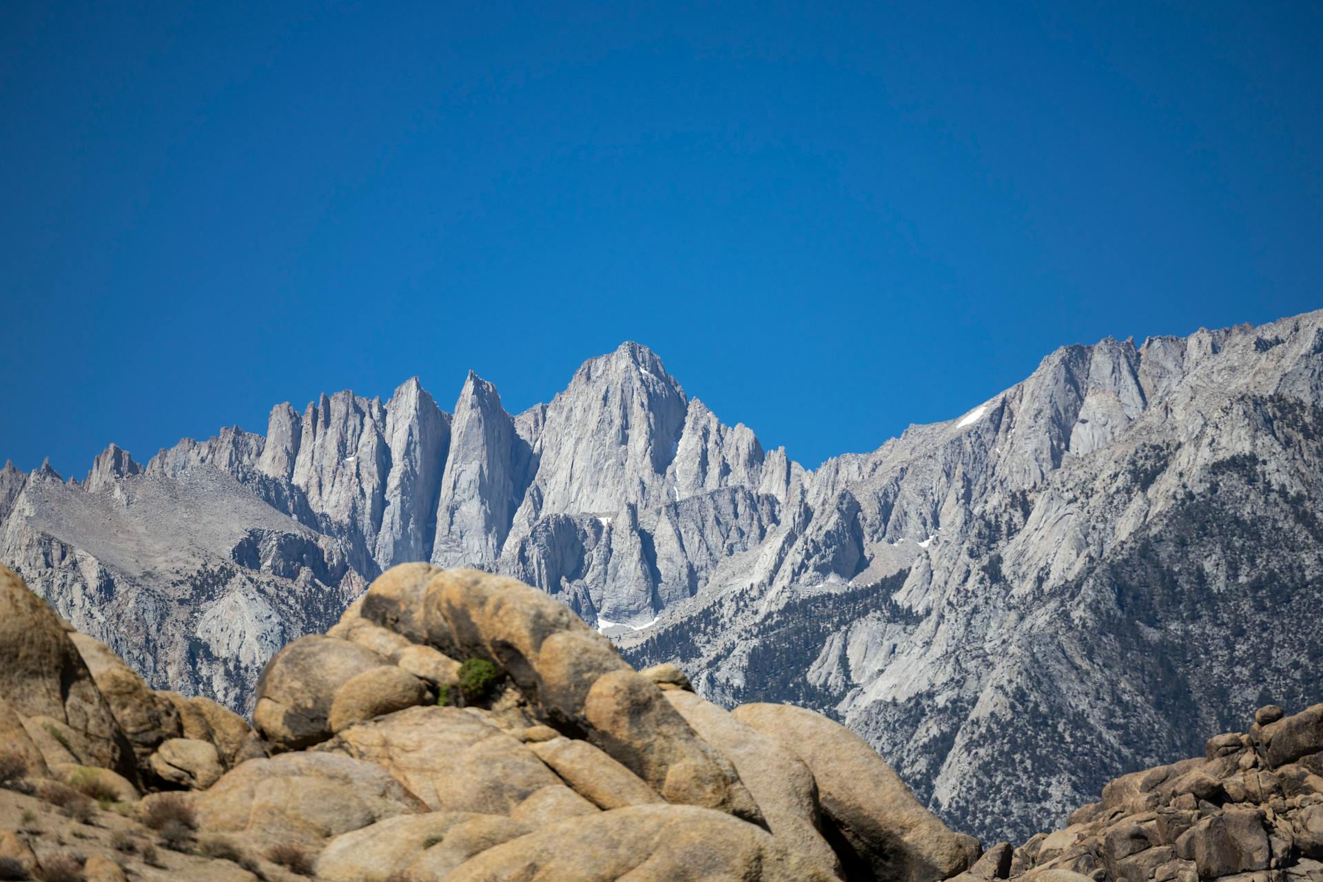 Capture the majestic Mount Whitney with its rugged peaks against a clear blue sky, showcasing natural beauty.