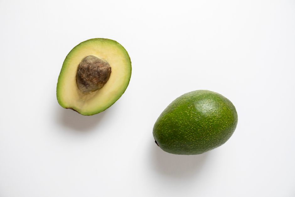 Close-up of a fresh halved avocado with a white background, showing rich texture.
