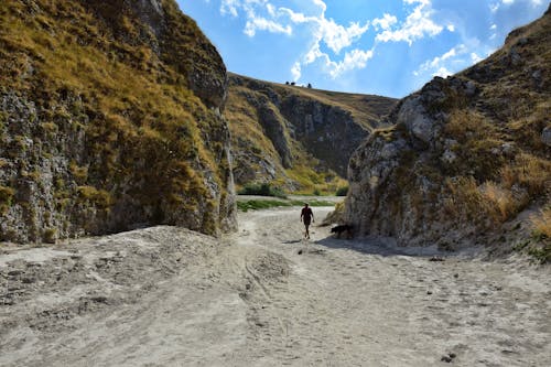 Person Hiking on Sand Footpath among Rocks