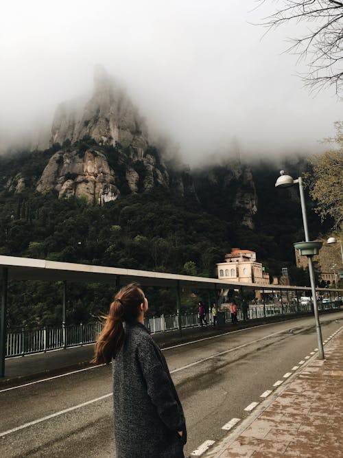 女人站在山附近穿黑夾克的照片