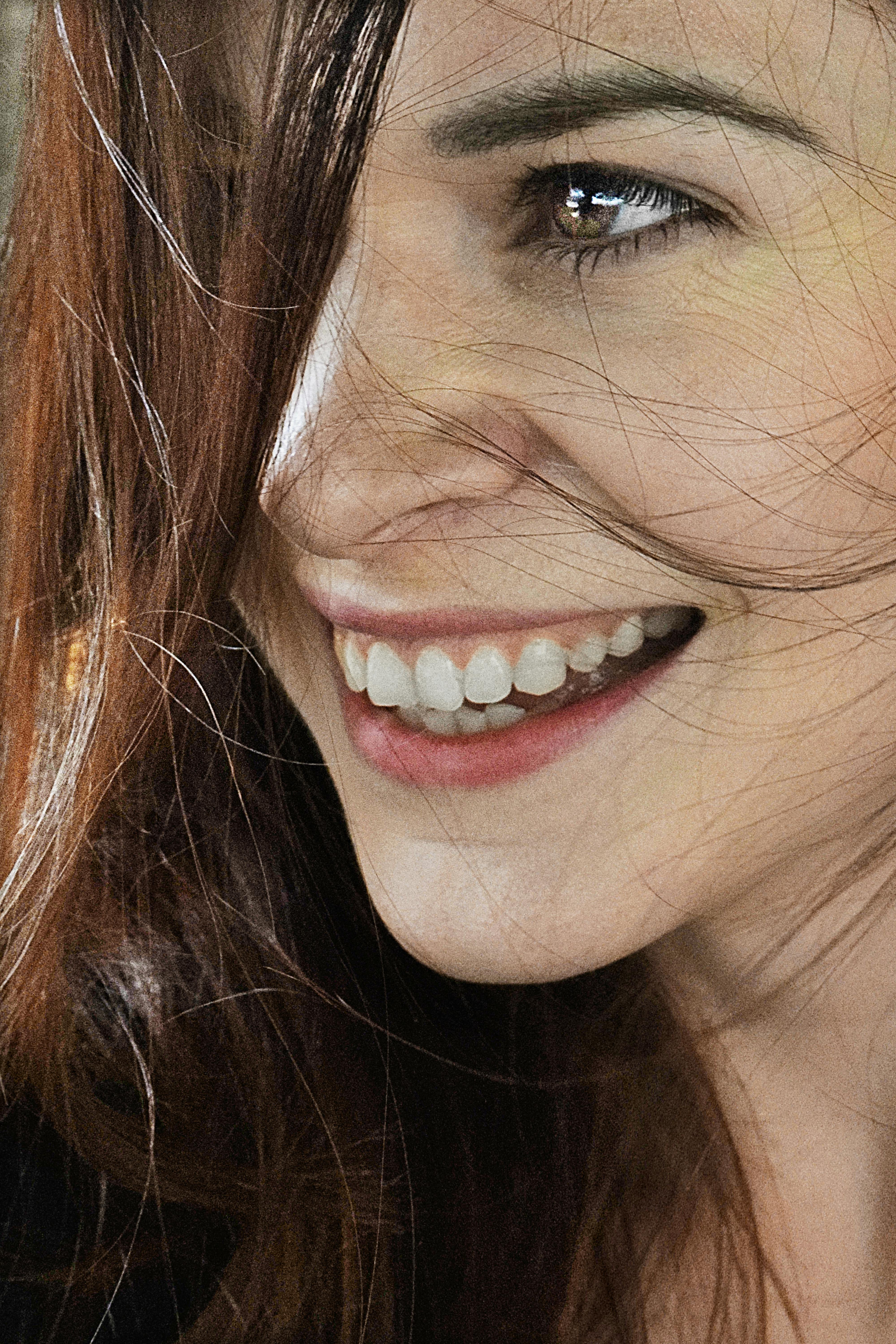 Close-up of a woman smiling with brown hair, capturing joy and natural beauty.