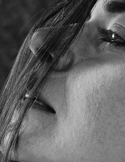 Free An expressive close-up of a woman's face with long hair, captured in black and white. Stock Photo