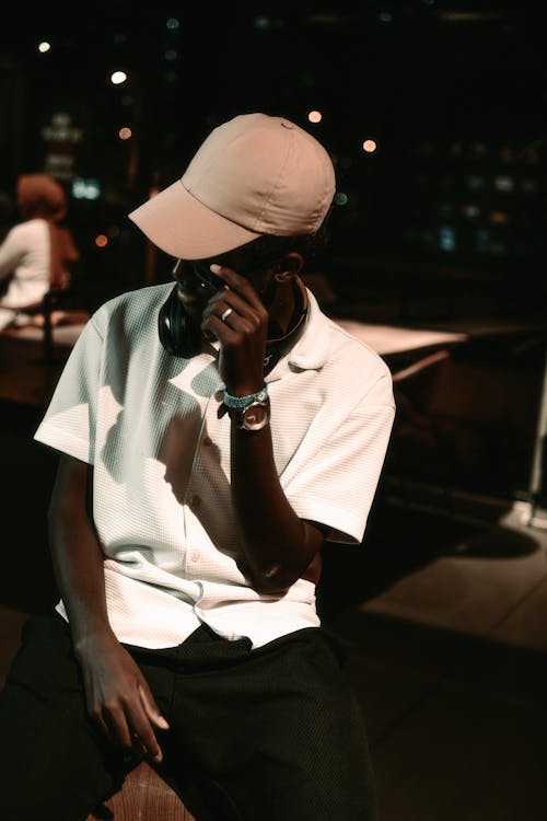 Man in White Shirt and Beige Baseball Cap Sitting in a Street Cafe