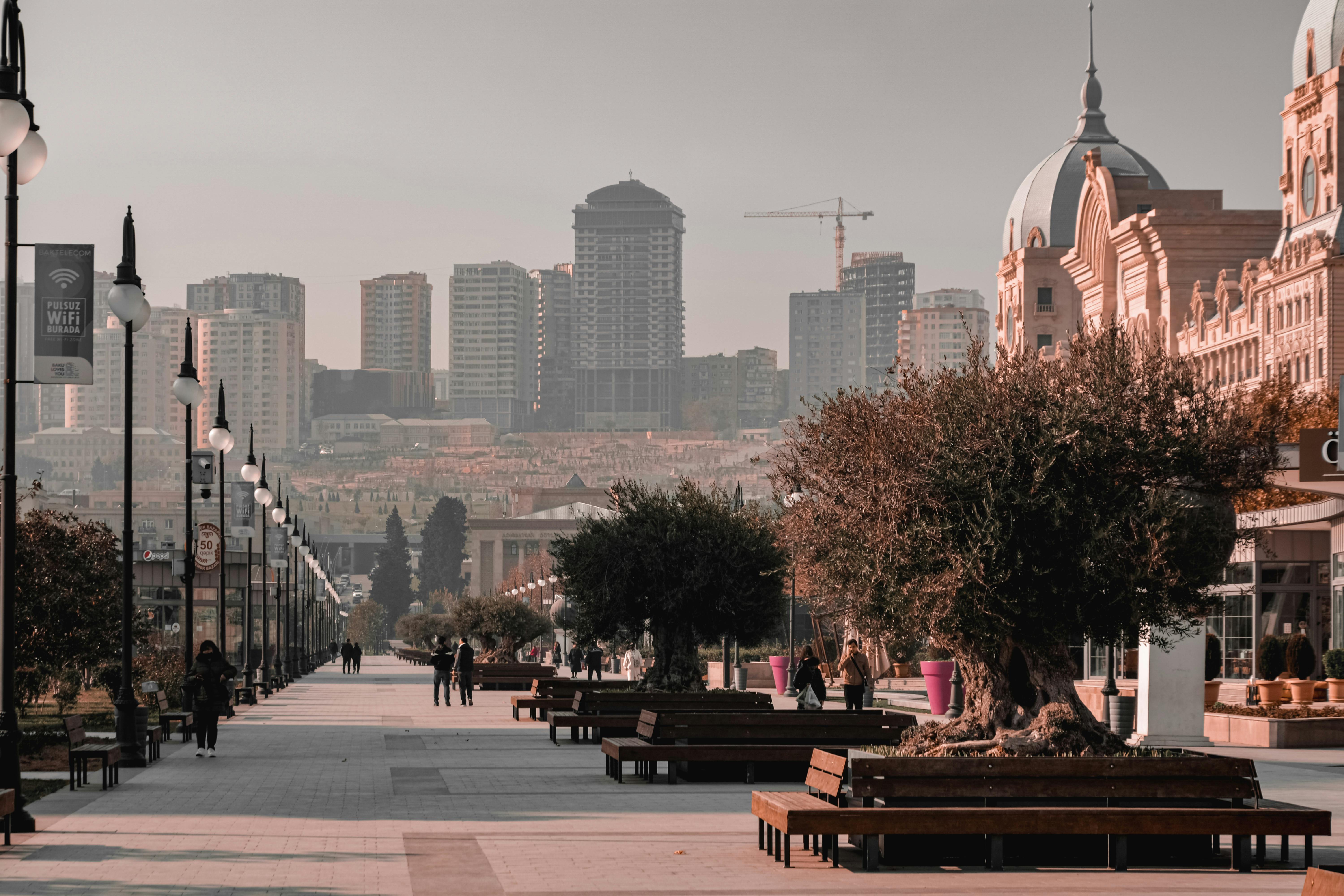 A bustling boulevard in Baku with people walking and the city skyline in the background.