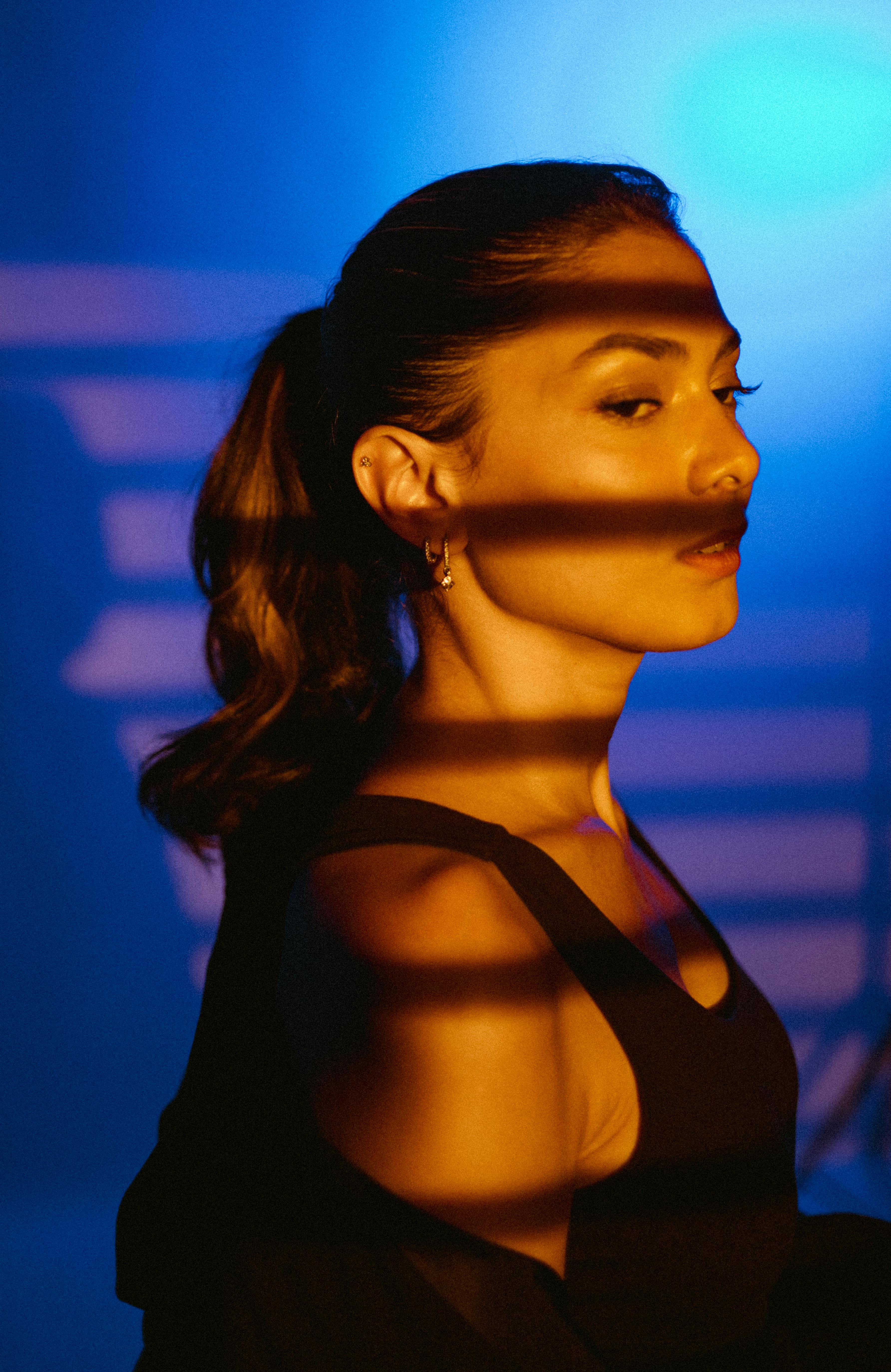 Artistic portrait of a woman with dramatic shadows in a studio setting.
