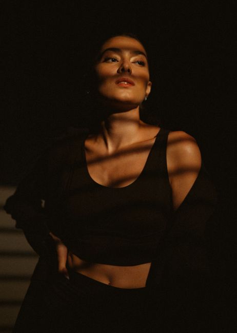 A model stands dramatically with shadows on her face, evoking mystery. Perfect for fashion shoots.