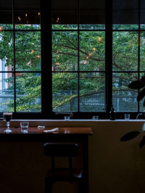Free Charming interior cafe photo showcasing greenery through large windows, perfect for relaxed atmospheres. Stock Photo