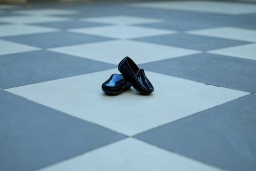 Free Stylish black shoes placed on a geometric checkered outdoor floor in Malegaon, India. Stock Photo