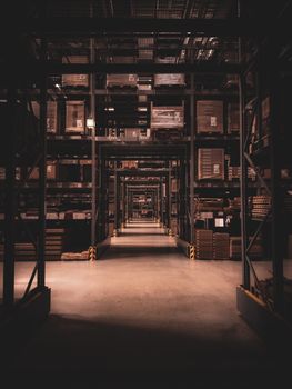 Dimly lit warehouse aisle in Berlin filled with large shelves and boxes, showcasing industrial organization.