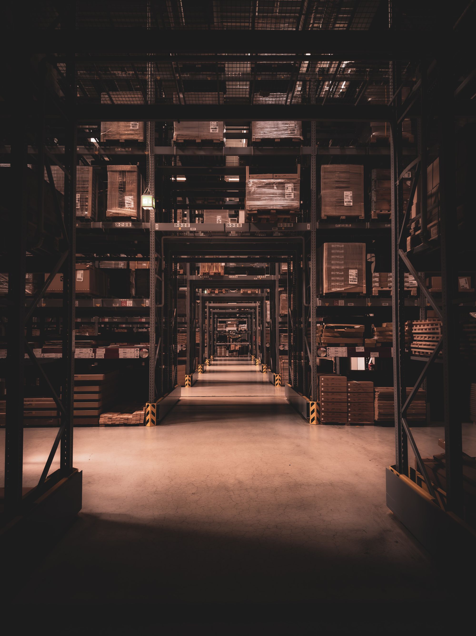 Long warehouse aisle of high racking in low light