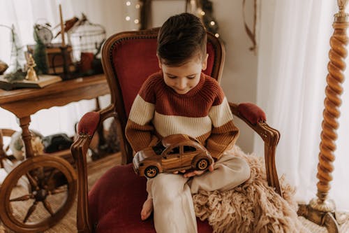 Boy in Sweater Sitting with Toy on Armchair