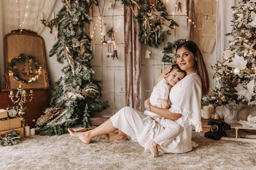 Mother Embracing Daughter Among Christmas Decorations