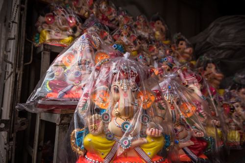 Free Vibrant Ganesh statues wrapped for sale at a Kolkata market, showcasing Indian culture and artistry. Stock Photo