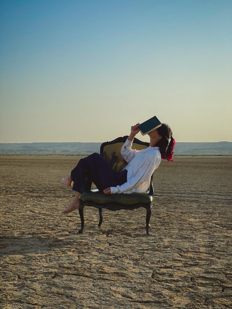 Woman With A Book On A Wide Old-fashioned Chair In The Desert