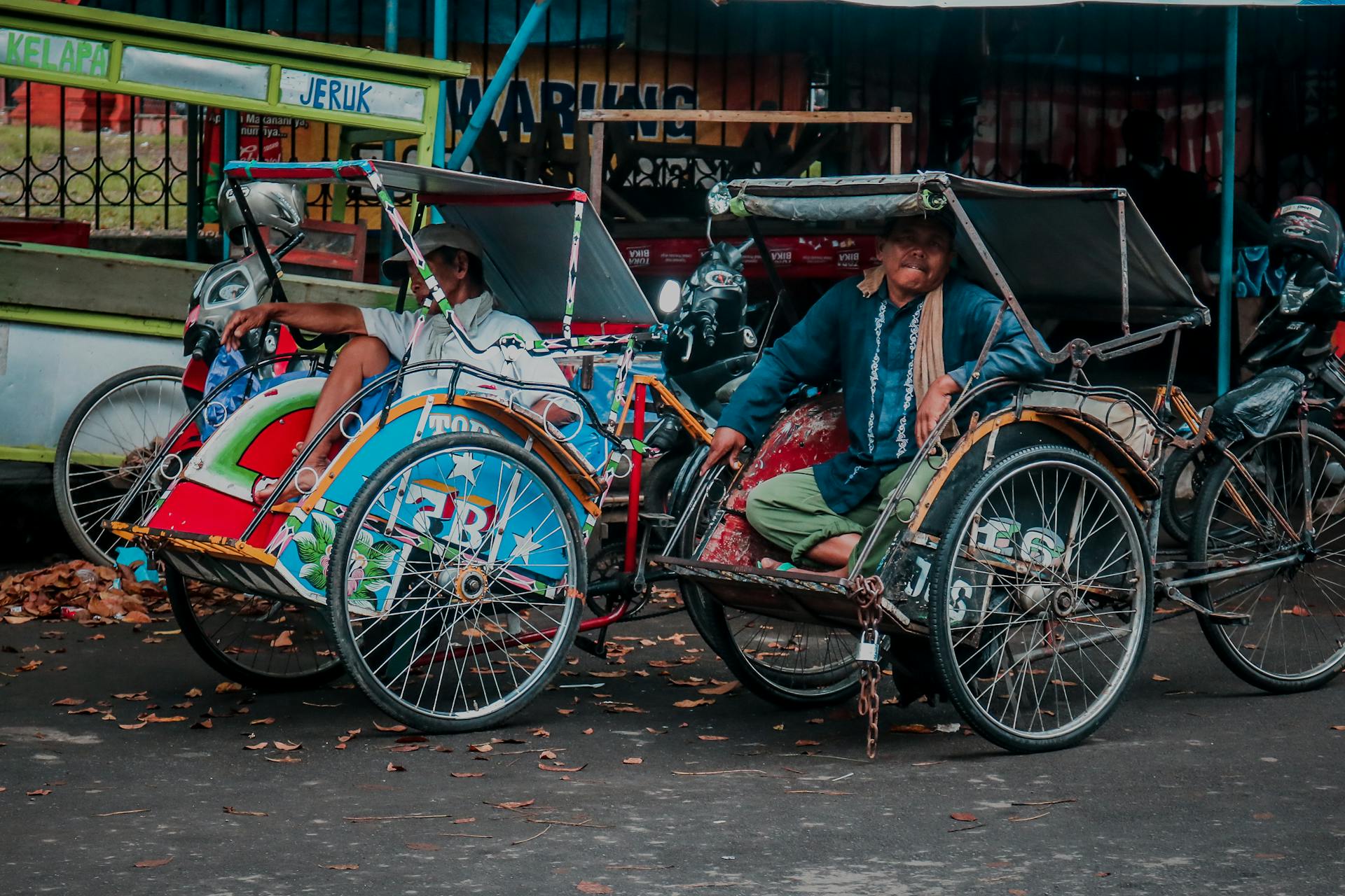 Vibrant rickshaws with drivers waiting in an Indonesian street market setting.