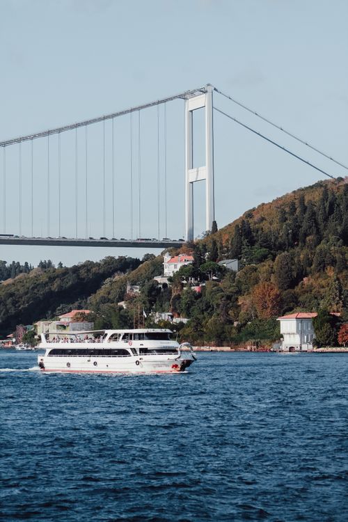 Free A boat sails under the Fatih Sultan Mehmet Bridge in Istanbul, Turkey, showcasing its architectural elegance. Stock Photo